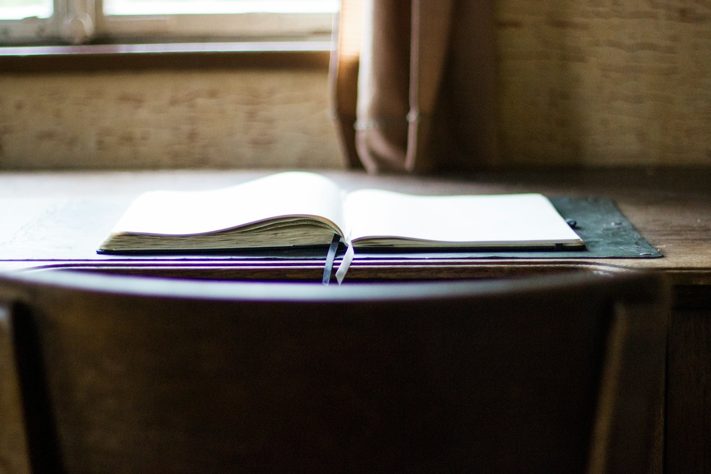 Open blank notebook resting on a rustic wooden desk.